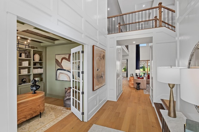 corridor featuring built in shelves, a towering ceiling, and hardwood / wood-style floors