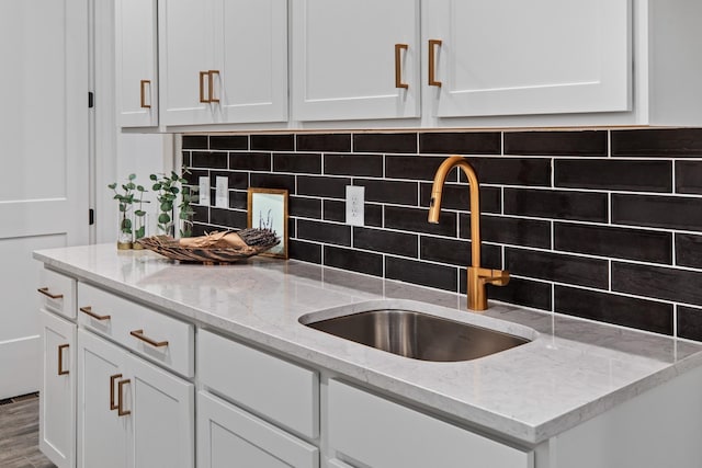 kitchen with decorative backsplash, light stone counters, and sink