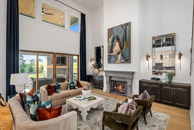 living room with ceiling fan, light hardwood / wood-style floors, and a high ceiling