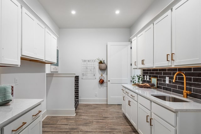 kitchen with white cabinets, tasteful backsplash, light stone countertops, and sink