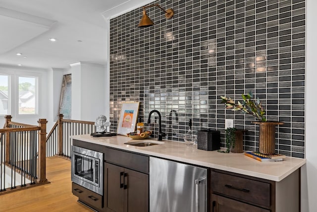 bar with refrigerator, tasteful backsplash, sink, light hardwood / wood-style flooring, and stainless steel microwave