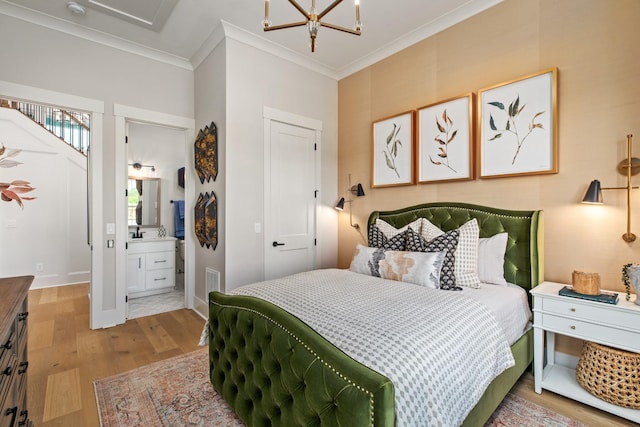 bedroom featuring connected bathroom, an inviting chandelier, light wood-type flooring, a closet, and ornamental molding