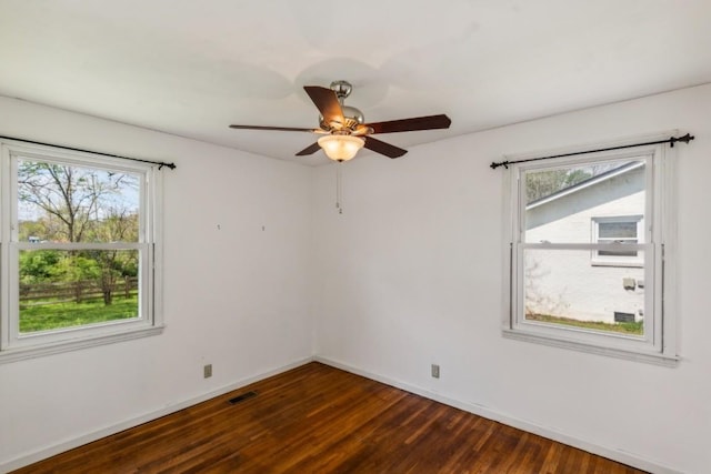 spare room featuring ceiling fan, plenty of natural light, and dark hardwood / wood-style floors