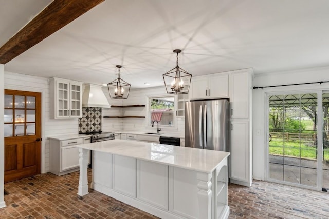 kitchen with a center island, stainless steel appliances, premium range hood, decorative light fixtures, and white cabinets