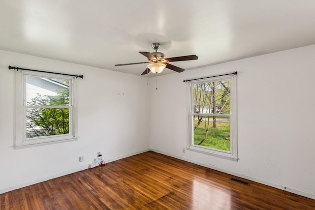 empty room with hardwood / wood-style flooring, ceiling fan, and a healthy amount of sunlight