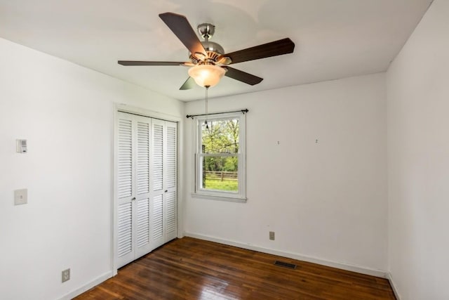 unfurnished bedroom with ceiling fan, a closet, and dark hardwood / wood-style floors