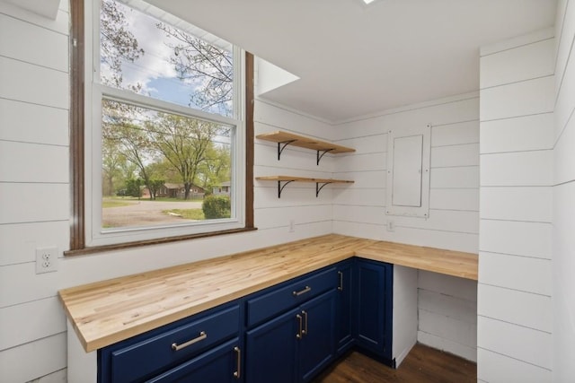 kitchen with wooden walls, dark wood-type flooring, blue cabinets, and butcher block counters