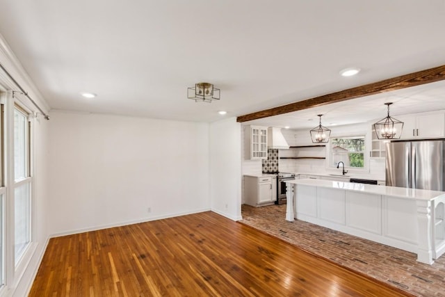 kitchen featuring white cabinetry, stainless steel appliances, pendant lighting, a kitchen island, and hardwood / wood-style flooring