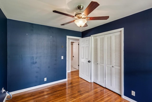 unfurnished bedroom with ceiling fan, a closet, and hardwood / wood-style floors