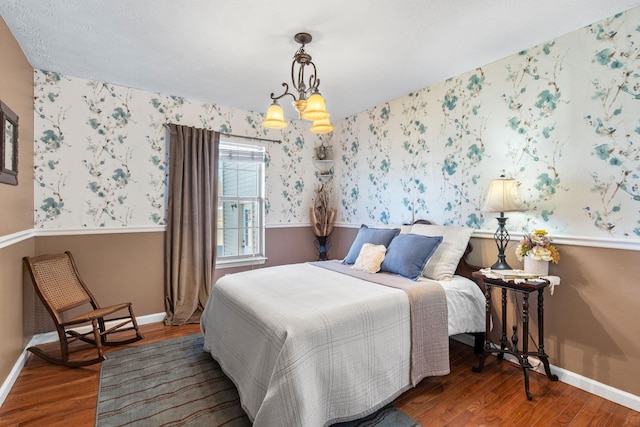 bedroom featuring baseboards, wood finished floors, and wallpapered walls