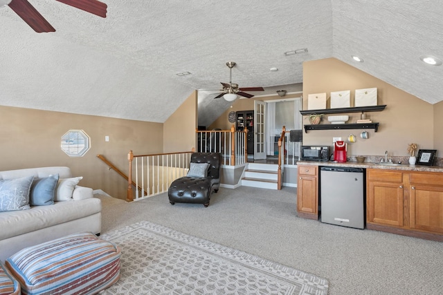 living room with a textured ceiling, light colored carpet, a ceiling fan, vaulted ceiling, and indoor wet bar