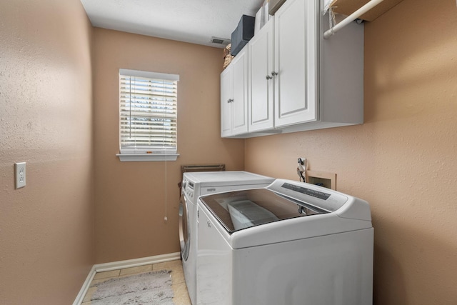 laundry room featuring cabinet space, baseboards, separate washer and dryer, and light tile patterned flooring