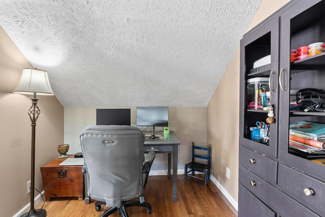 office featuring lofted ceiling, a textured ceiling, baseboards, and wood finished floors