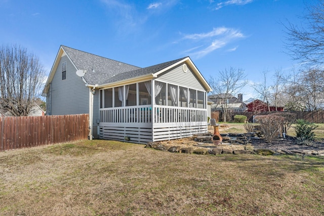 rear view of property with a shingled roof, a lawn, fence, and a sunroom