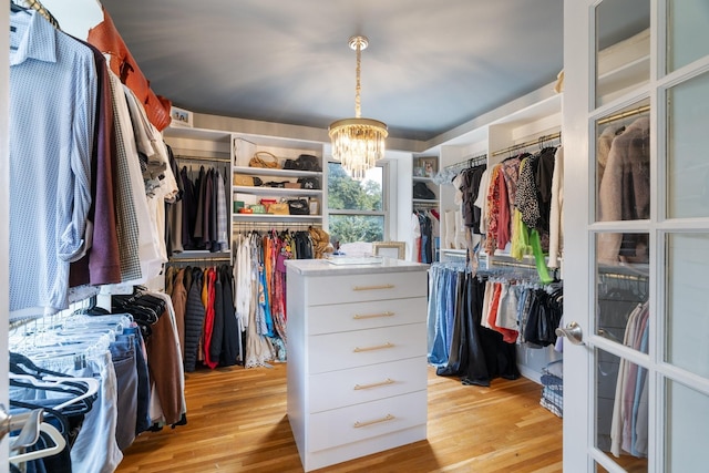 spacious closet featuring a chandelier and light hardwood / wood-style flooring