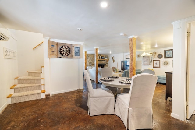 dining area featuring decorative columns and a stone fireplace