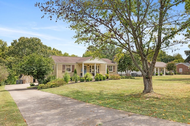 ranch-style house featuring covered porch, a front yard, and a storage unit