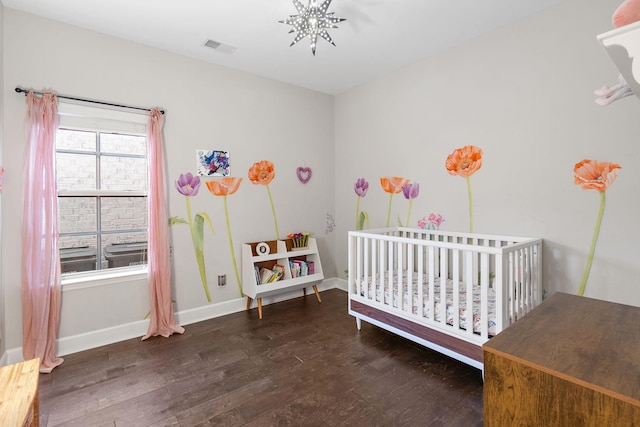 bedroom with dark hardwood / wood-style flooring and a nursery area