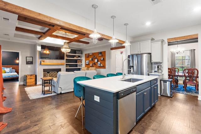 kitchen featuring stainless steel appliances, blue cabinets, pendant lighting, a kitchen island with sink, and a fireplace