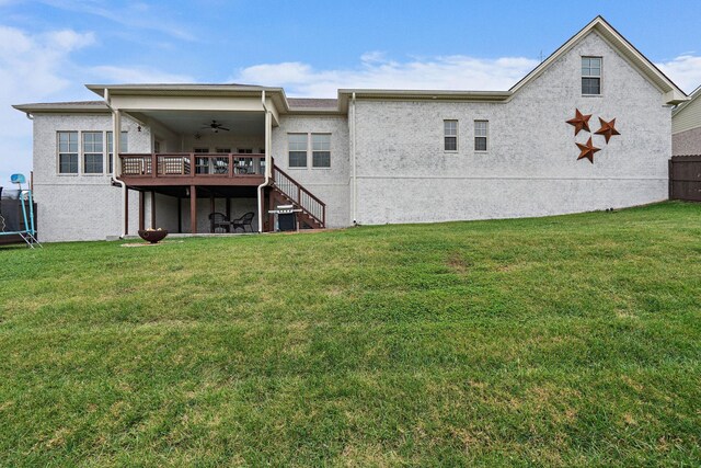 rear view of house featuring a yard, a trampoline, a deck, and ceiling fan