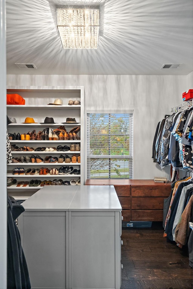 spacious closet featuring a notable chandelier and dark hardwood / wood-style flooring