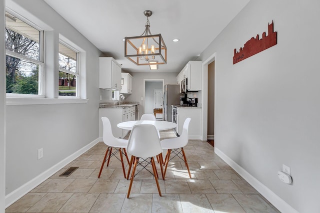 tiled dining room with an inviting chandelier and sink