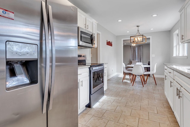 kitchen with an inviting chandelier, hanging light fixtures, appliances with stainless steel finishes, light stone counters, and white cabinetry