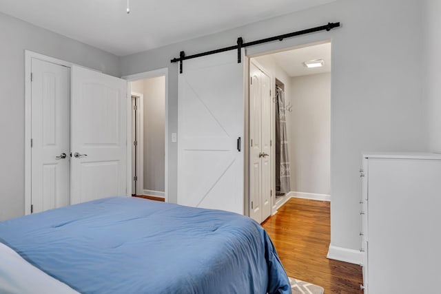 bedroom featuring hardwood / wood-style flooring, a barn door, and a closet