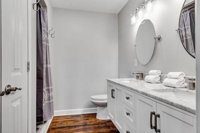 bathroom featuring wood-type flooring, vanity, and toilet