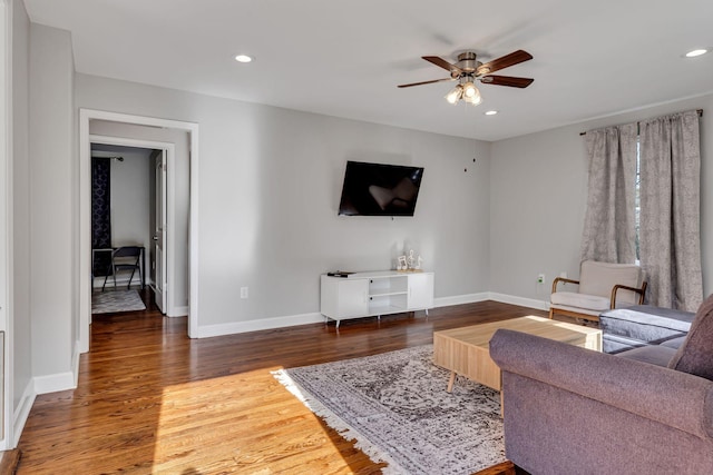 living room with ceiling fan and dark hardwood / wood-style flooring