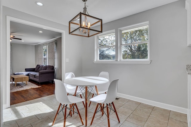 dining room with light tile patterned floors, ceiling fan with notable chandelier, and a wealth of natural light