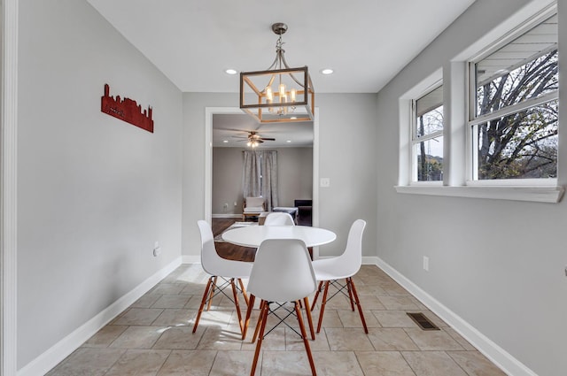 tiled dining room with ceiling fan with notable chandelier