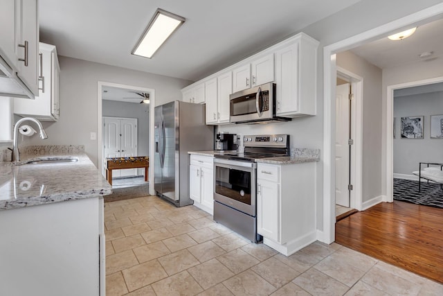 kitchen with light stone countertops, white cabinetry, sink, and appliances with stainless steel finishes