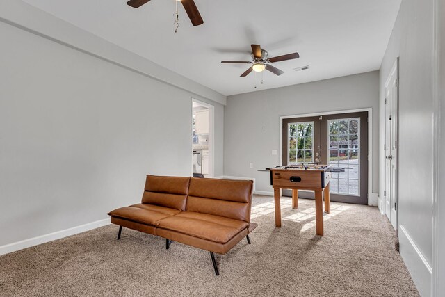 living area featuring light carpet, french doors, and ceiling fan