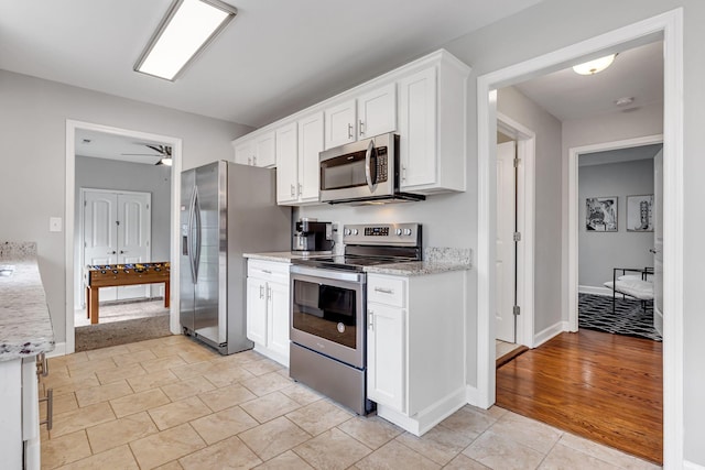 kitchen featuring white cabinetry, stainless steel appliances, and light tile patterned floors