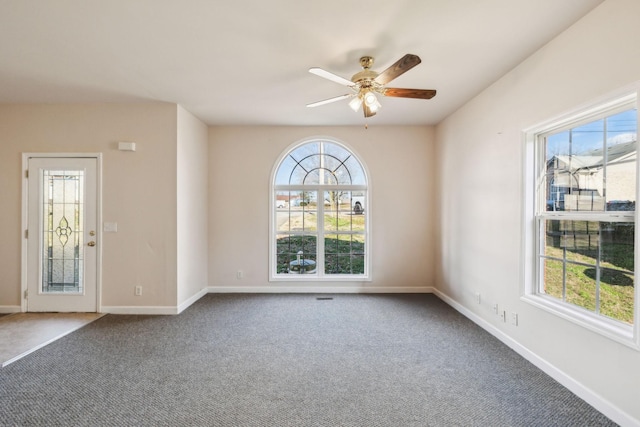 empty room featuring carpet floors, ceiling fan, and a healthy amount of sunlight