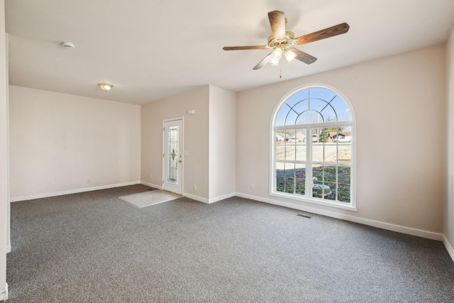 unfurnished room with ceiling fan and dark colored carpet