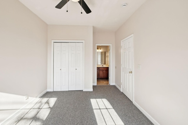 unfurnished bedroom featuring connected bathroom, ceiling fan, a closet, and dark carpet