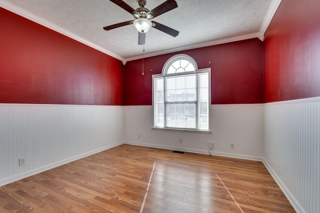 unfurnished room featuring a textured ceiling, hardwood / wood-style flooring, ceiling fan, and crown molding