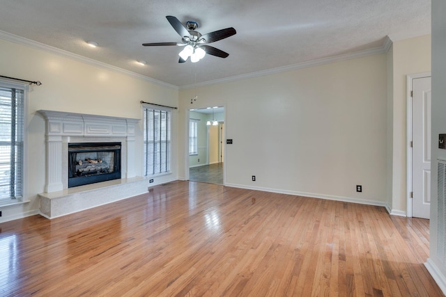 unfurnished living room with ceiling fan, ornamental molding, a textured ceiling, and light hardwood / wood-style flooring