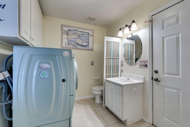 bathroom with tile patterned flooring, vanity, toilet, and washer / clothes dryer