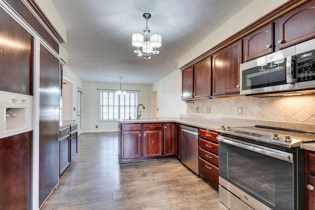 kitchen with backsplash, a chandelier, decorative light fixtures, and appliances with stainless steel finishes