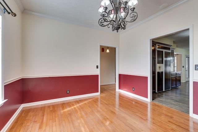 unfurnished room featuring wood-type flooring, an inviting chandelier, and ornamental molding