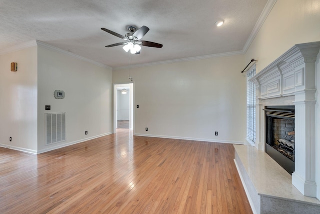 unfurnished living room featuring a high end fireplace, a textured ceiling, ceiling fan, and crown molding