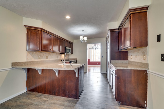 kitchen featuring a breakfast bar, stainless steel appliances, dark wood-type flooring, a notable chandelier, and hanging light fixtures