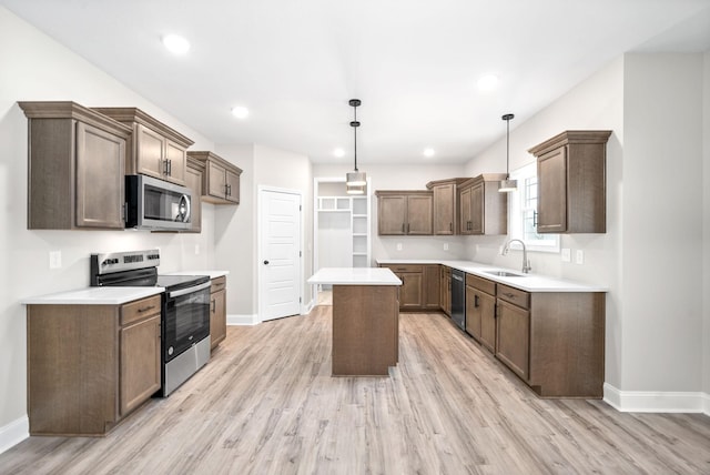 kitchen featuring stainless steel appliances, a sink, light wood-style flooring, and a center island