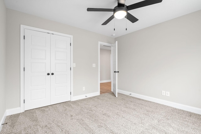 unfurnished bedroom with carpet, baseboards, ceiling fan, and a closet