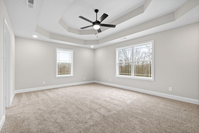 empty room with carpet, a raised ceiling, and ceiling fan