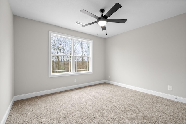 carpeted spare room with visible vents, ceiling fan, and baseboards