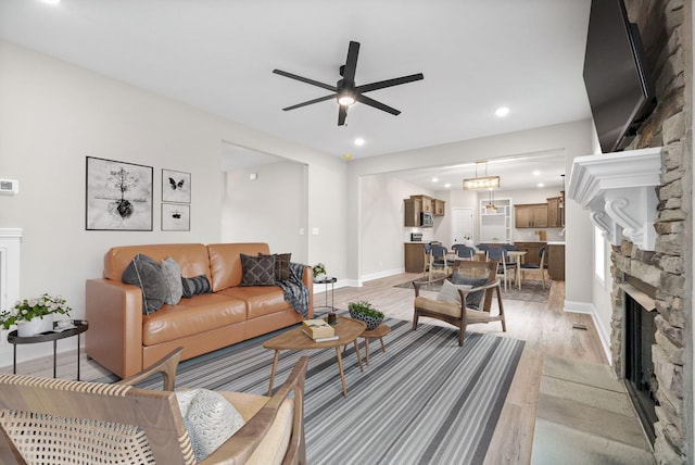 living room with recessed lighting, a fireplace, a ceiling fan, baseboards, and light wood-style floors